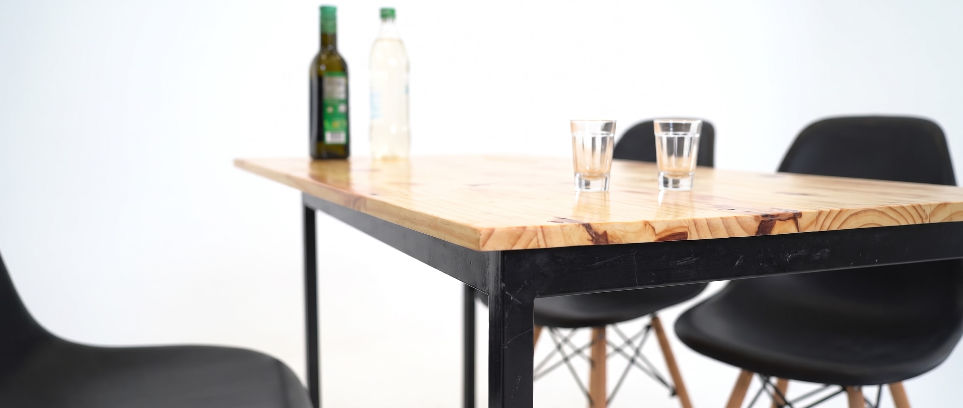 Borda da mesa de pinho e um pé de metal preto, com dois copos vazios.